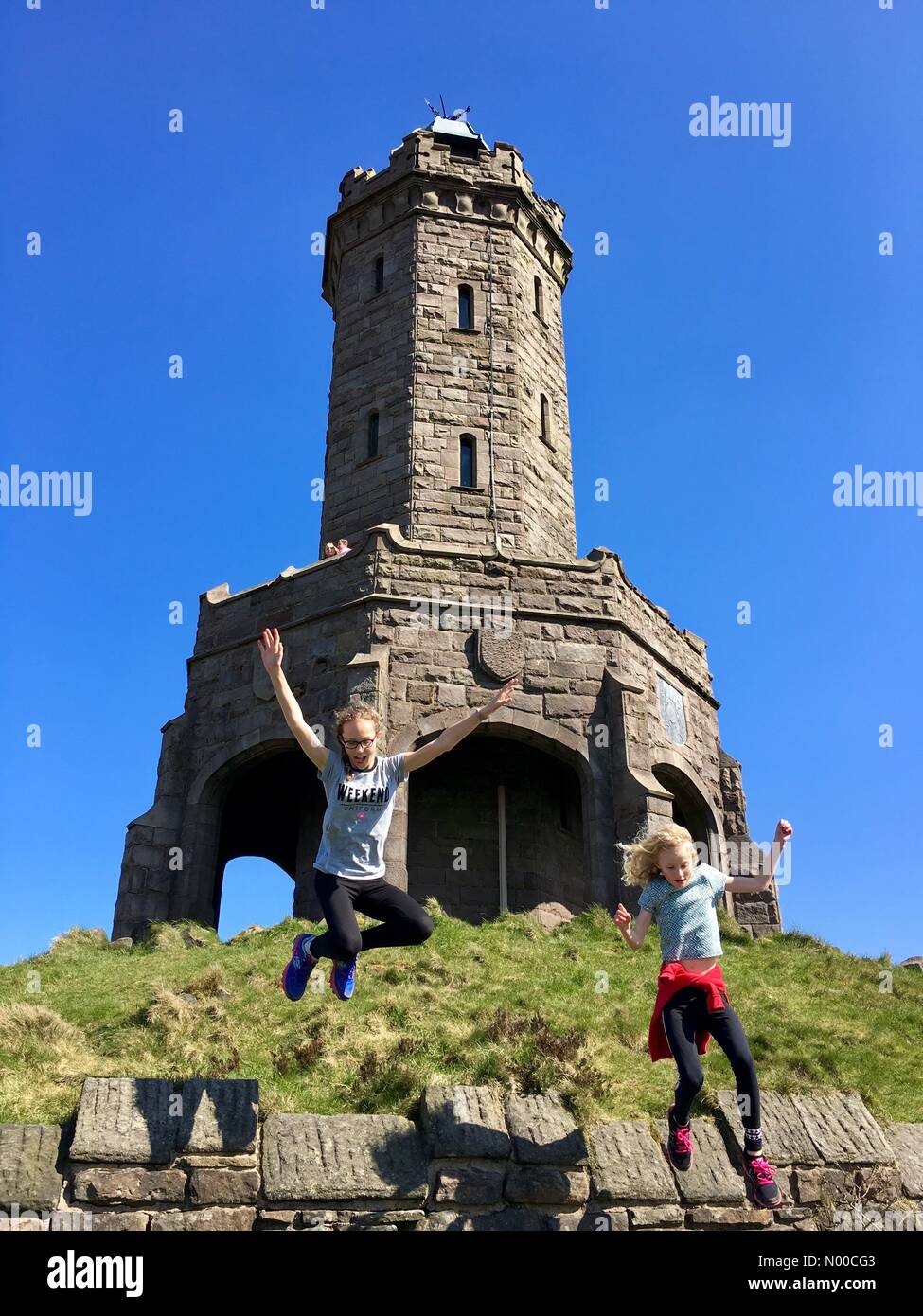 UK-Wetter: sonniger Tag in Blackburn, Lancashire. Zwei Mädchen, die Spaß in der Sonne am Darwen Jubilee Tower auf die Mauren über Blackburn. Stockfoto