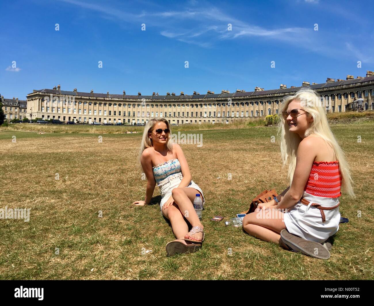 Wetter in Großbritannien, England, 7. Juli 2018 zwei junge Frauen aus der Bretagne in sonniger warmer Tag vor dem Royal Crescent in der Badewanne, wo Temperaturen vorhergesagt sind bis 29 Grad erreichen. Stockfoto
