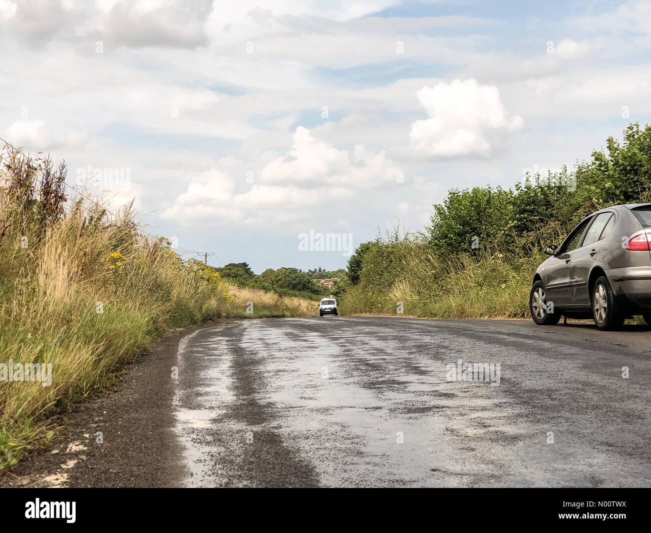 UK Wetter: Geschmolzene Straßen in Godalming. Tuesley Lane Godalming. 24. Juli 2018. Hitzewelle im Südosten heute. Wasser auf den Straßen weiter schmelzen in Godalming, Surrey zu verhindern. Credit: jamesjagger/StockimoNews/Alamy leben Nachrichten Stockfoto