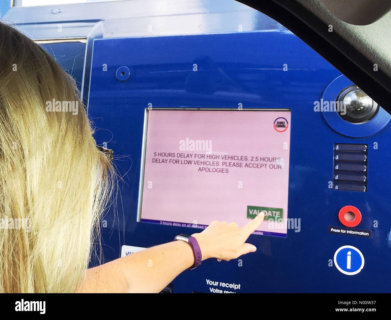 Eurotunnel Terminal Ashford, Kent, Großbritannien. Eine Frau drückt die Taste die schwerwiegenden Verzögerungen, dass Reisende grüße Kontrolle in der Eurotunnel aufgrund der Unterbrechung des Dienstes zu bestätigen. Stockfoto
