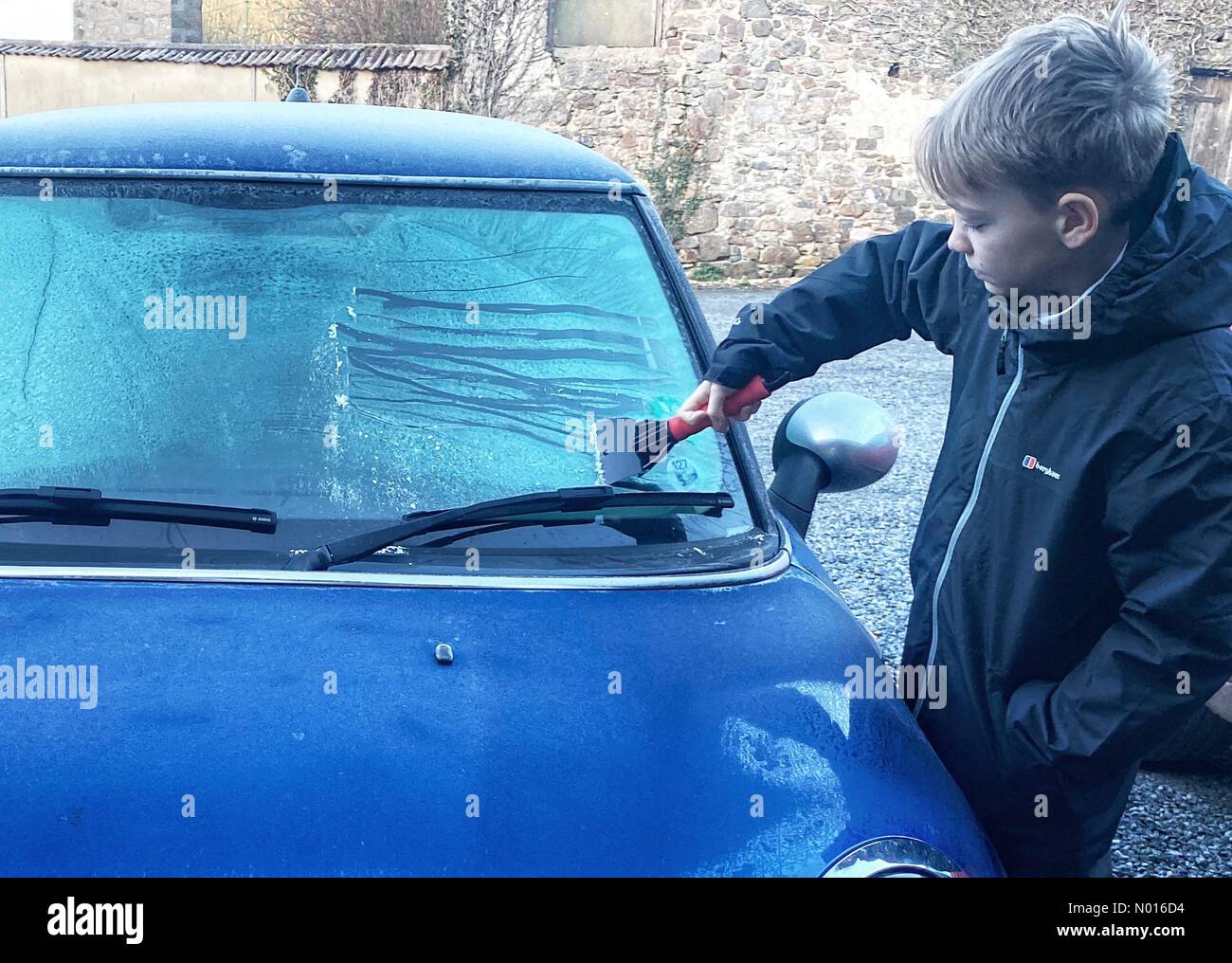 UK Wetter: Jack Porter kratzt Eis von einer gefrorenen Autoscheibe vor der Schule in frostigen Doddiscombsleigh, Devon, Großbritannien. 11th. Februar 2022. Credit nidpor/Alamy Live News Credit: Nidpor/StockimoNews/Alamy Live News Stockfoto