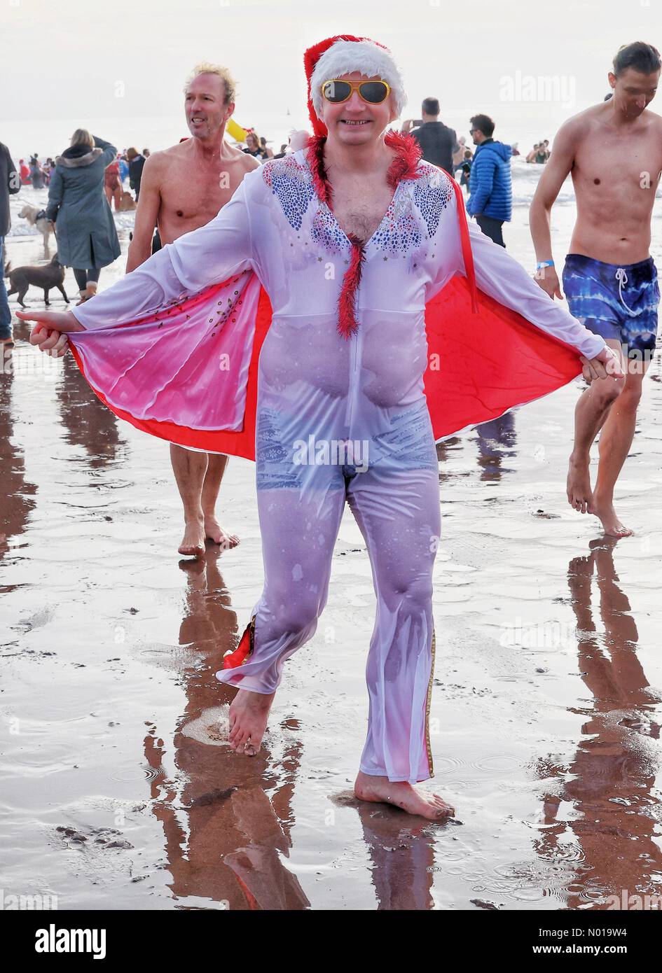 Farbenfrohe Menschenmassen überfluten den Teignmouth Strand für das beliebte jährliche Boxing Day Dip, das lokal als RNLI „Walk in the Sea“ bekannt ist. Teignmouth, Devon, Großbritannien. 26. Dezember 2023. Credit Nidpor Credit: Nidpor/StockimoNews/Alamy Live News Stockfoto