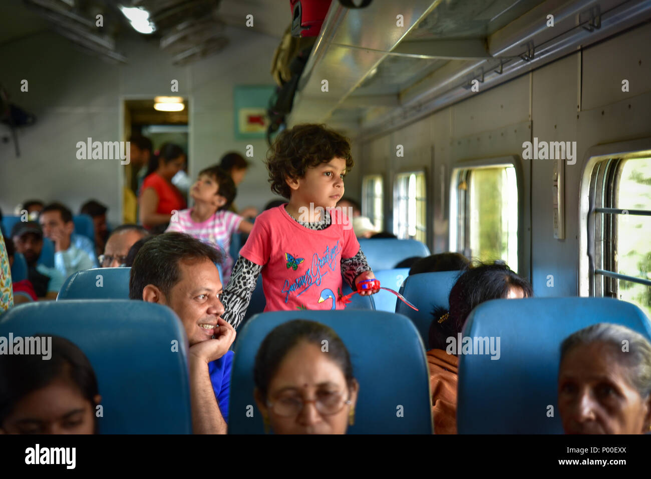 Ein Mädchen und ihr Vater im Zug blicken vor das Fenster in Indien Stockfoto