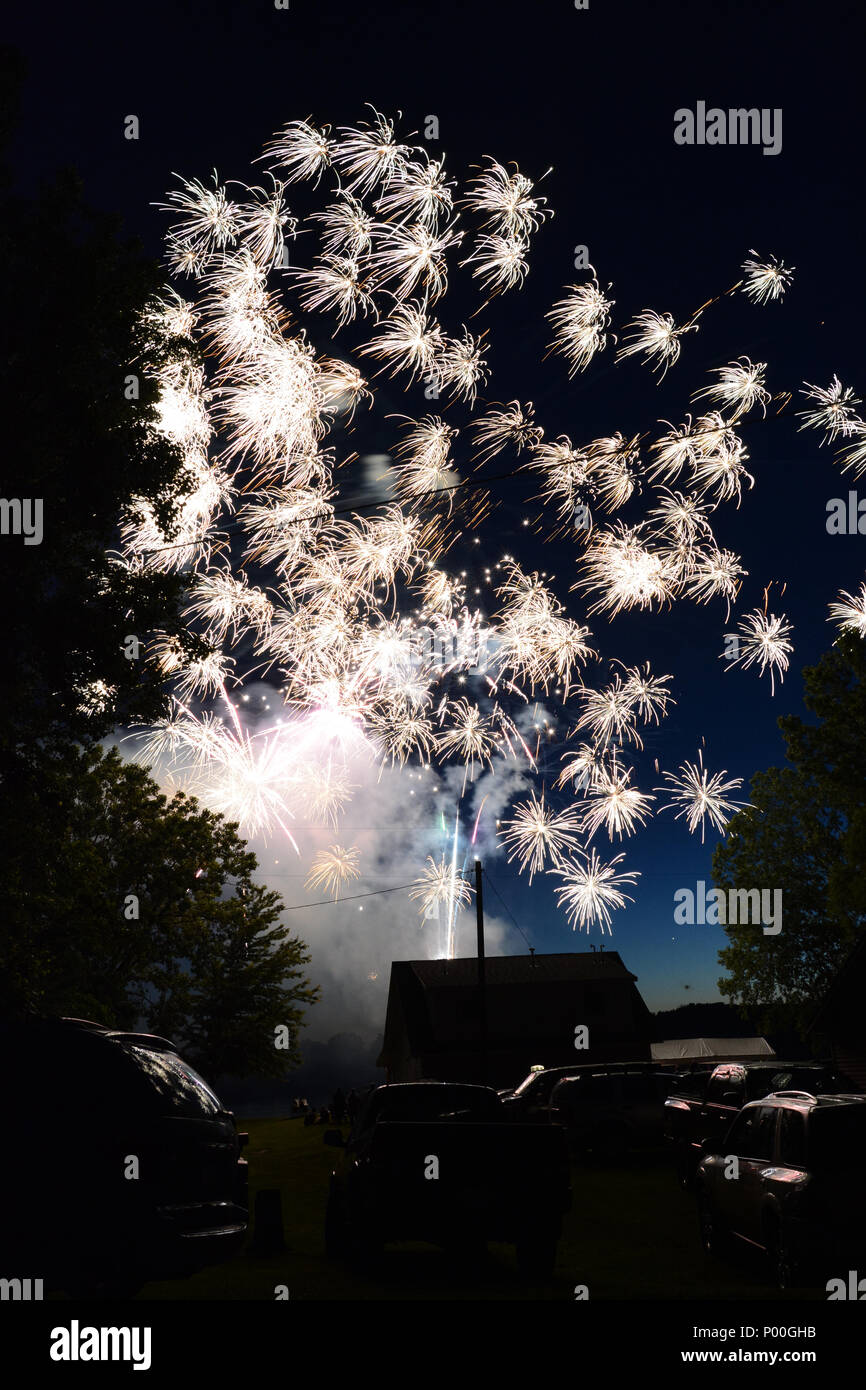 Buntes Feuerwerk den Nachthimmel über eine kleine Stadt. Stockfoto