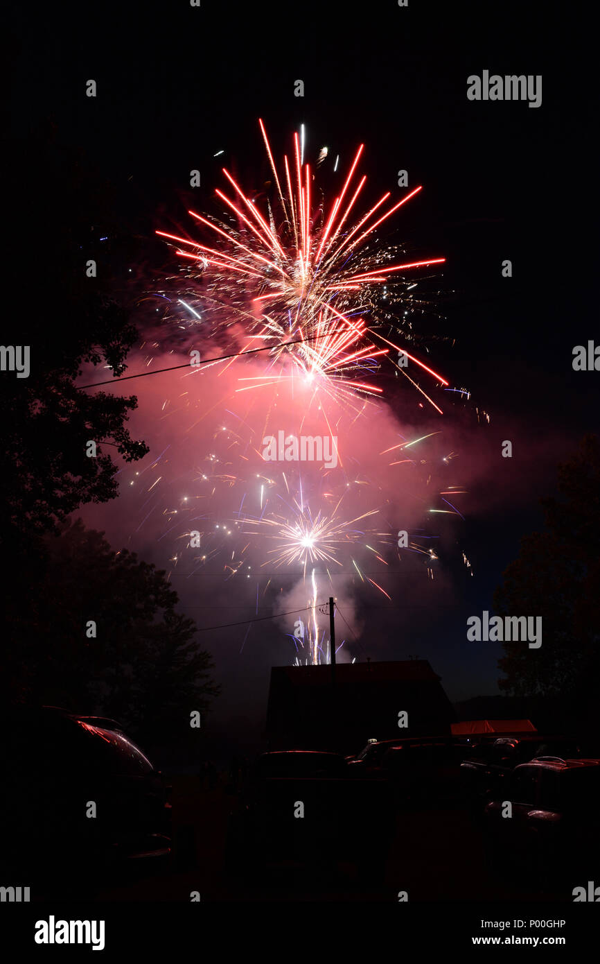 Buntes Feuerwerk den Nachthimmel über eine kleine Stadt. Stockfoto