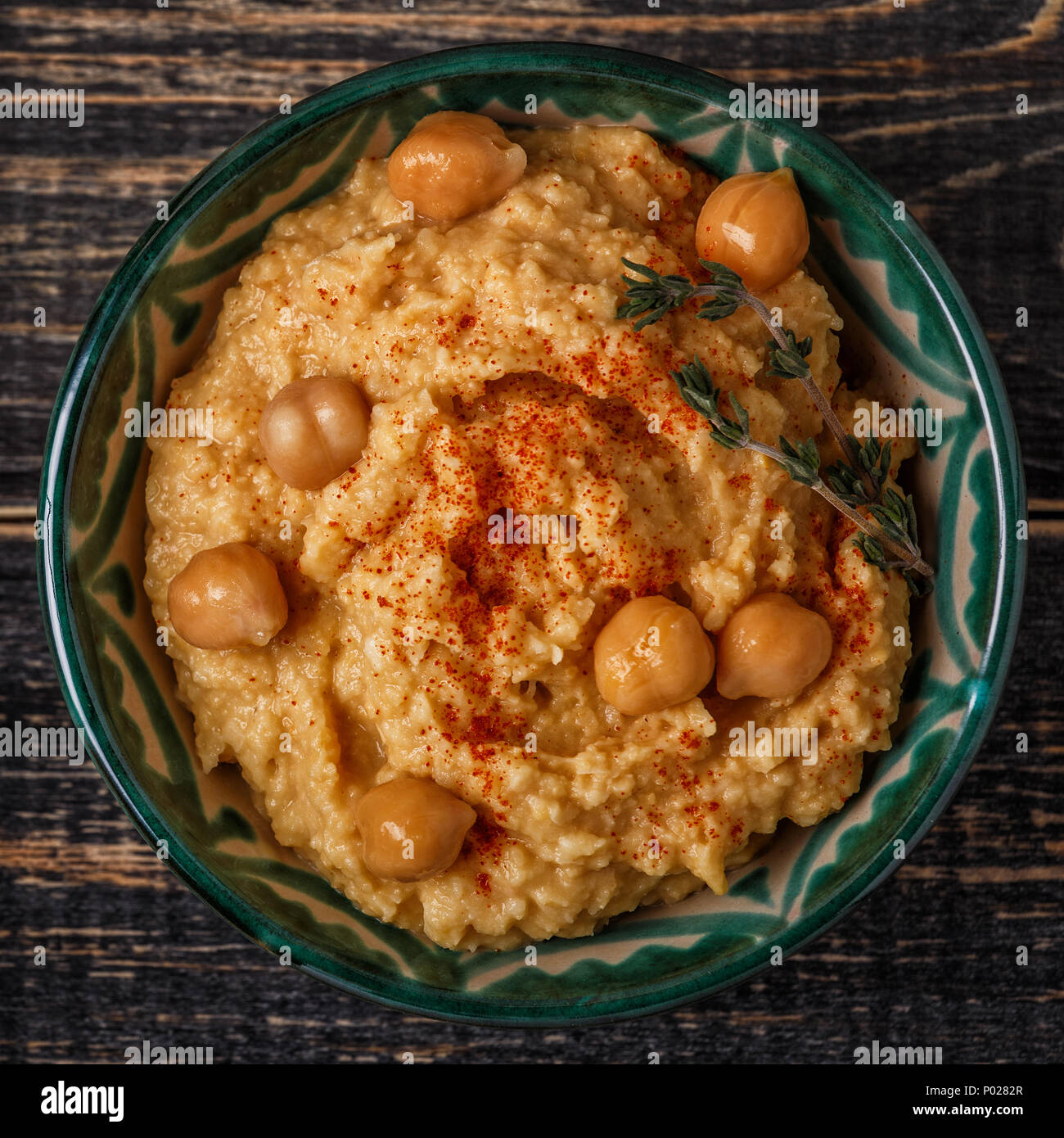 Pürierte Kichererbsen Dip mit tahini, Zitrone, Knoblauch, Olivenöl, Thymian und Paprika auf Holztisch, Ansicht von oben. Stockfoto