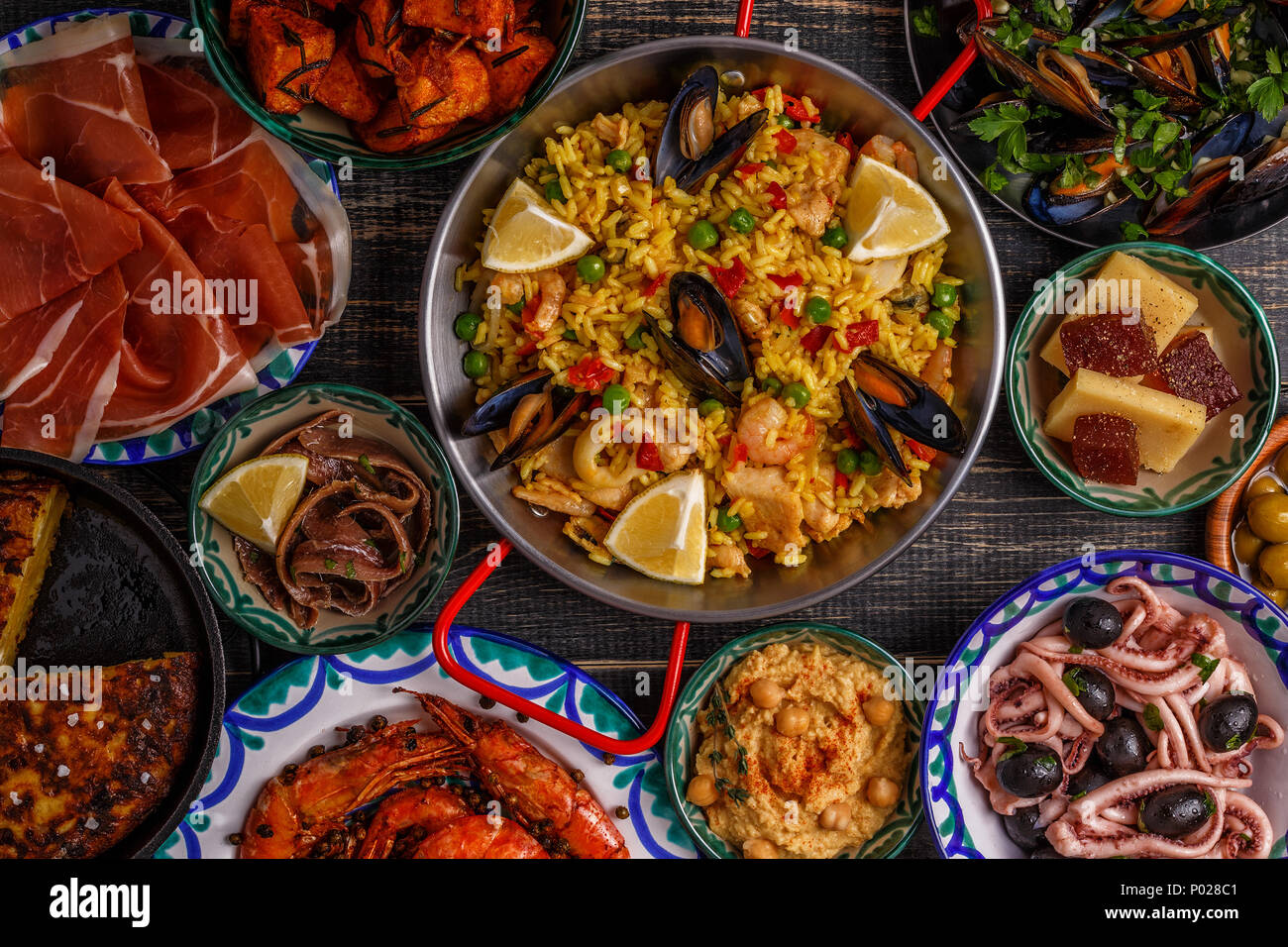 Typische spanische Tapas Konzept. Konzept gehören Scheiben jamon, Schüsseln mit Oliven, Sardellen, würzige Kartoffeln, pürierte Kichererbsen, Garnelen, Tintenfisch, der manche Stockfoto