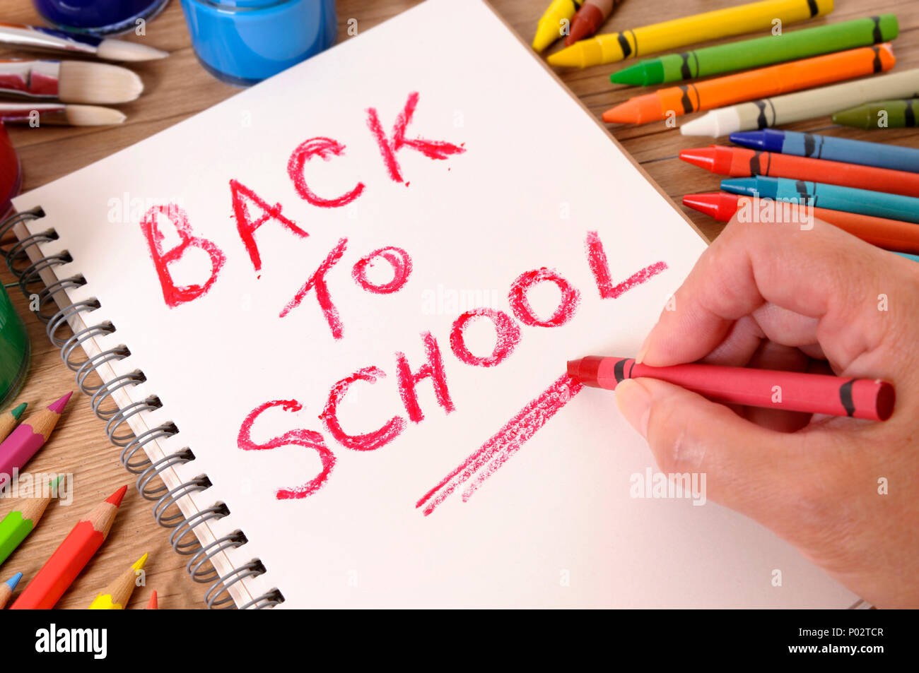 Die Worte zurück in die Schule, auf ein weißes Notebook mit verschiedenen Farben, Kreiden und Stifte geschrieben. Selektive konzentrieren. Stockfoto