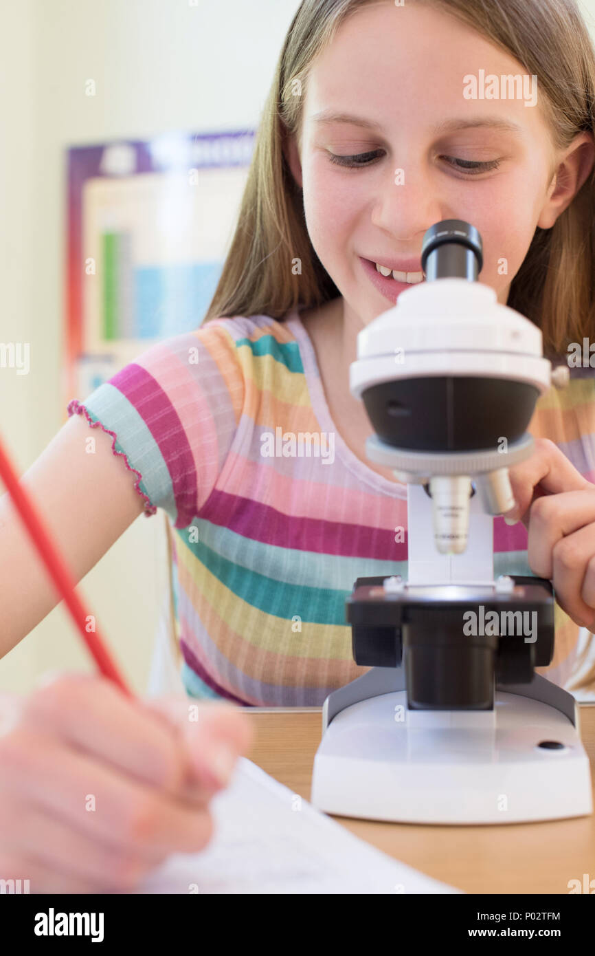 Studentin mit Mikroskop im naturwissenschaftlichen Unterricht Stockfoto