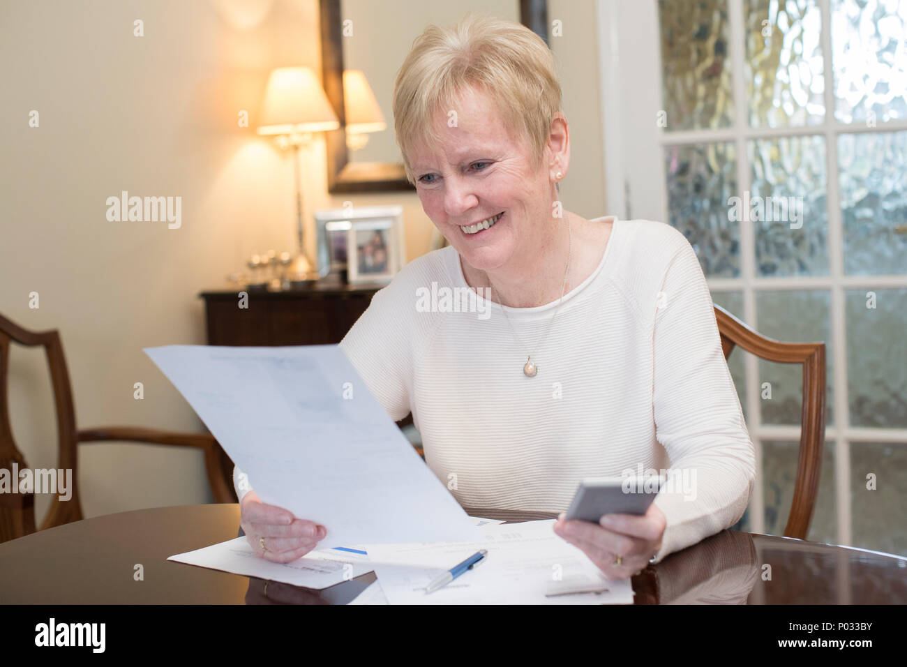 Gerne ältere Frau, die Überprüfung der inländischen Finanzen zu Hause Stockfoto
