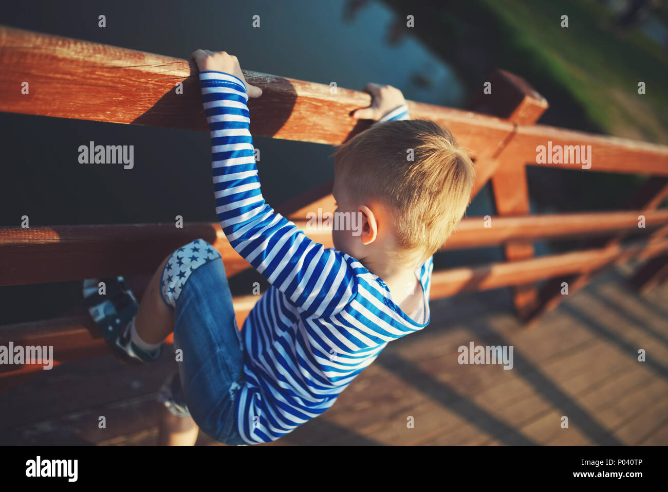 kleinen Jungen über den Zaun klettern Stockfoto