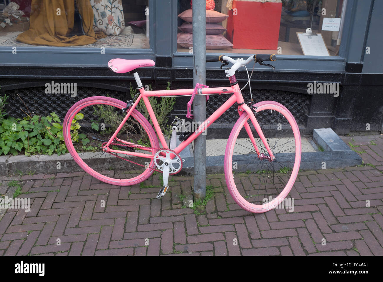 Eine gemalte rosa Fahrrad gegen Pol in der Straße in Amsterdam gesperrt Stockfoto