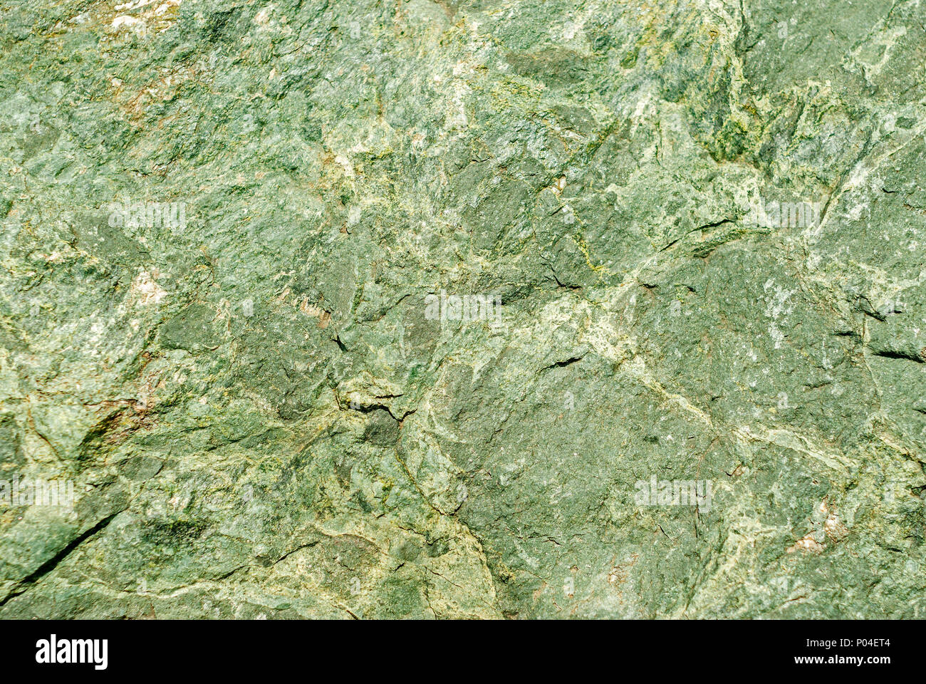 Hintergrund, Textur - raue Oberfläche des Cliff von serpentinite, Naturstein mit einem grünen Farbstich Stockfoto