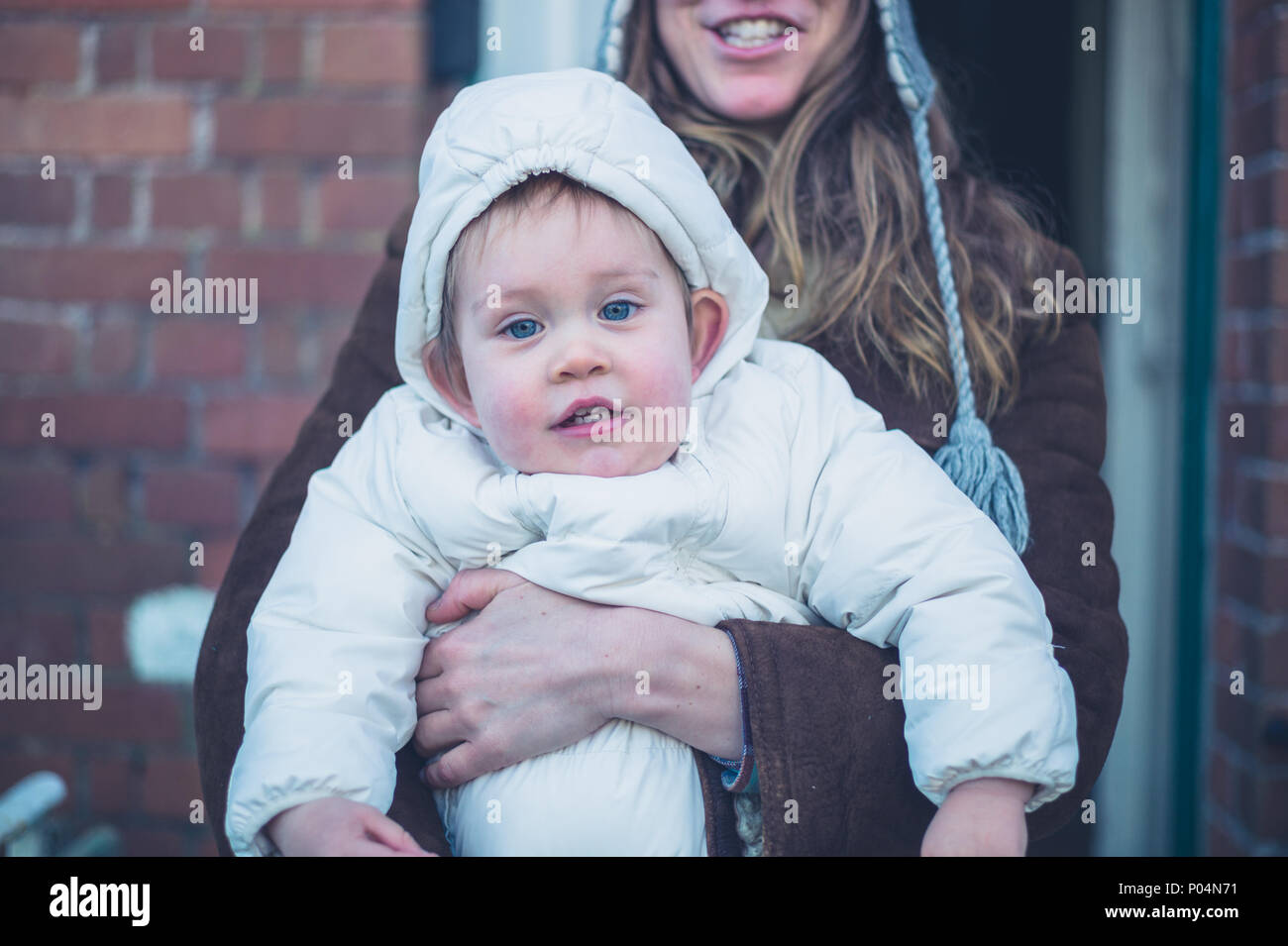Eine junge Mutter ist draußen mit ihr herzlich Baby im Winter gekleidet Stockfoto