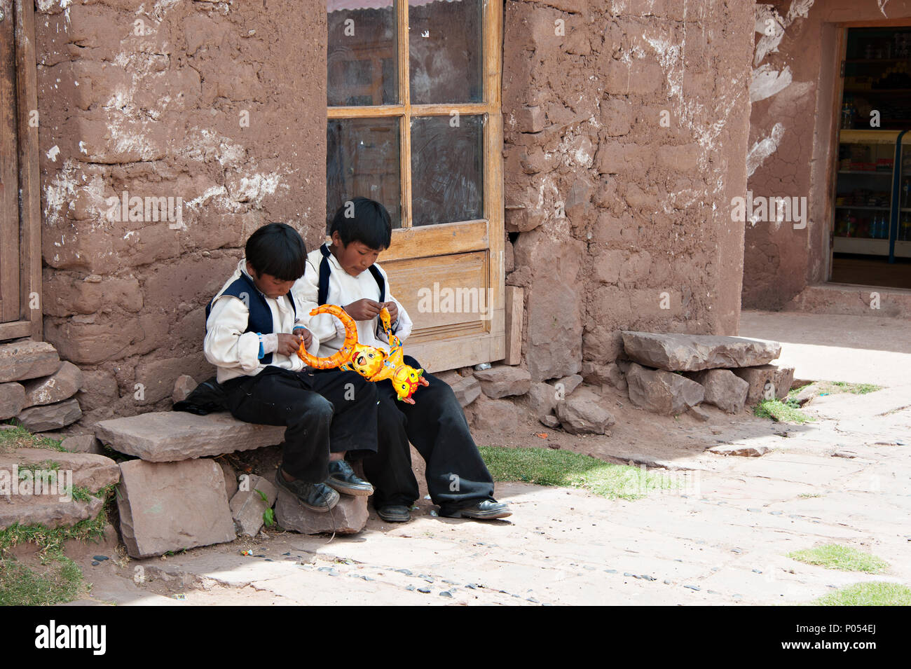 Zwei school Jungen warten auf Taquile Insel gesammelt werden, den Titicacasee. Peru Stockfoto