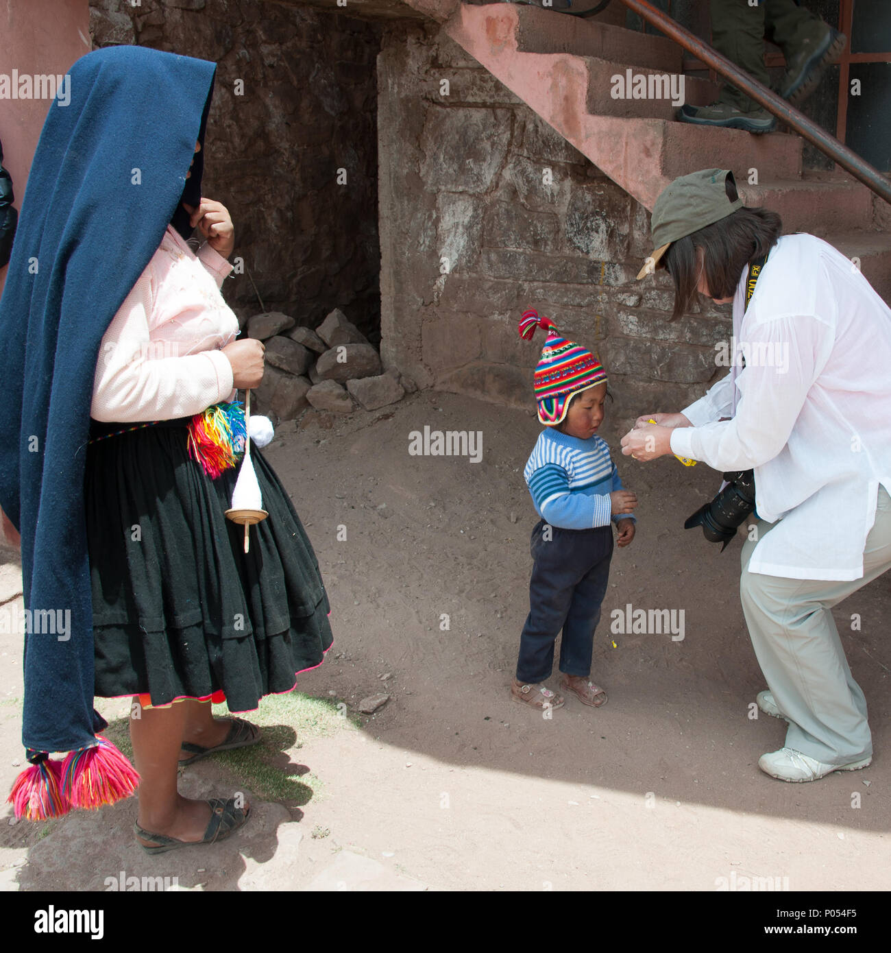 Mutter und ihr Kind Süßigkeiten Süßigkeiten aus ein Tourist auf Taquile Insel, den Titicacasee. Peru Stockfoto