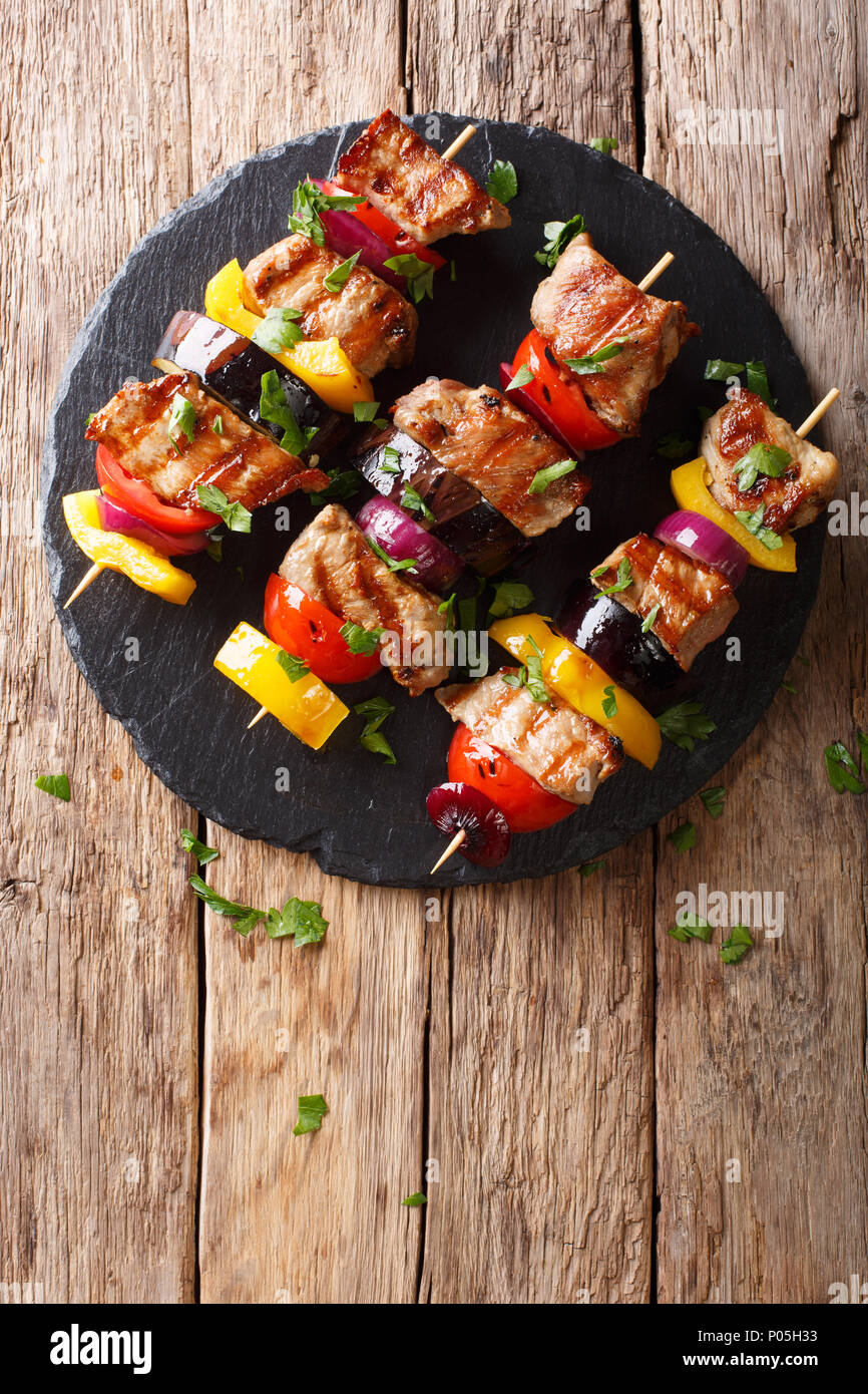 Leckere heiße Grill Shish Kebab aus Schweinefleisch mit Gemüse, serviert  auf einem Schiefer Platte close-up auf einem Tisch. Senkrechte Draufsicht  von oben Stockfotografie - Alamy