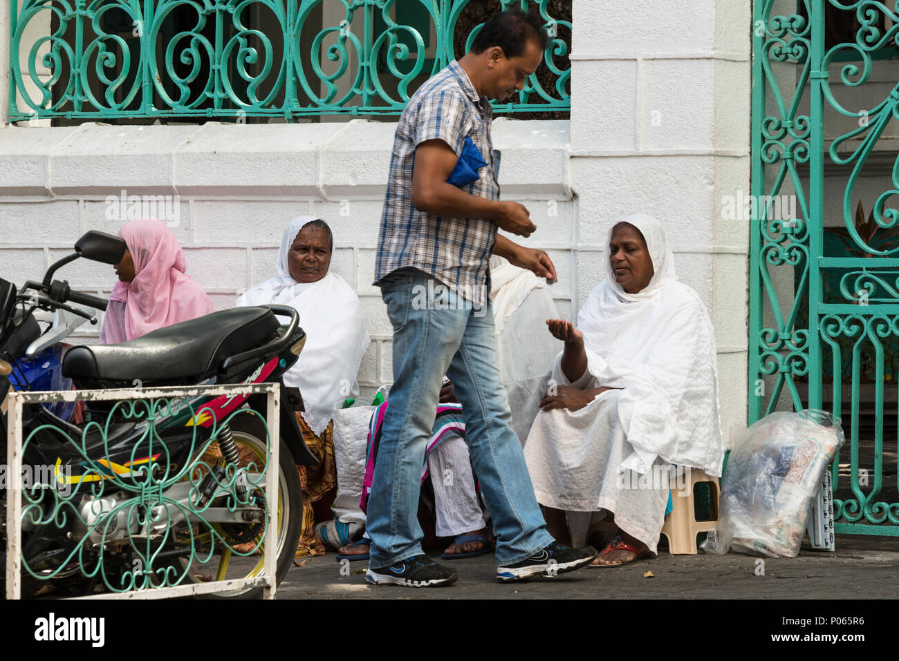Ein Passant Geld geben zu einer Gruppe von Frauen sitzen auf der Straße warten auf Almosen außerhalb Jummah Mosque an einem Freitag, Port Louis, Mauritius Stockfoto