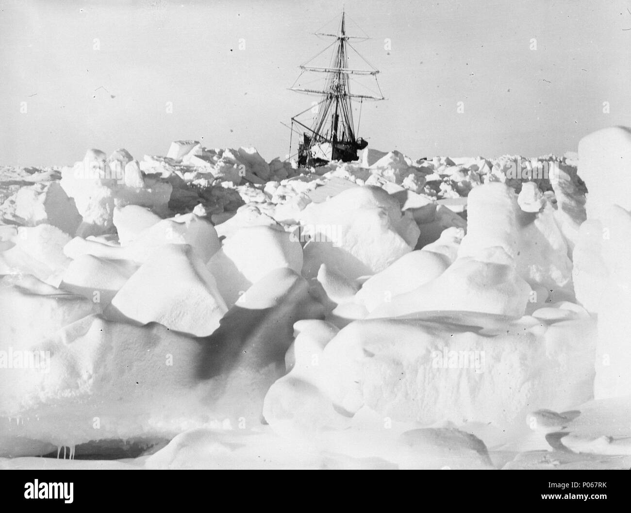 . Englisch: Eine ferne Bow View von 'Ausdauer' (1912) in die eisscholle Blick aus dem Eis Hängematten in Richtung Bug von 'Ausdauer' (1912), eine hölzerne Hilfs Entdeckung Schiff eingefroren, in der Ferne. Das Schiff hat auf einer kleinen Liste an Steuerbord. Die gebrochene hügeligen Ice Pack zeigt den Druck der Eisschollen. Ein entfernter Bow View von 'Ausdauer' (1912), in dem Eis eingefroren. Ca. August 1915. James Francis Hurley 96 eine ferne Bow View von 'Ausdauer' (1912) in die eisscholle RMG-P00016 eingefroren Stockfoto