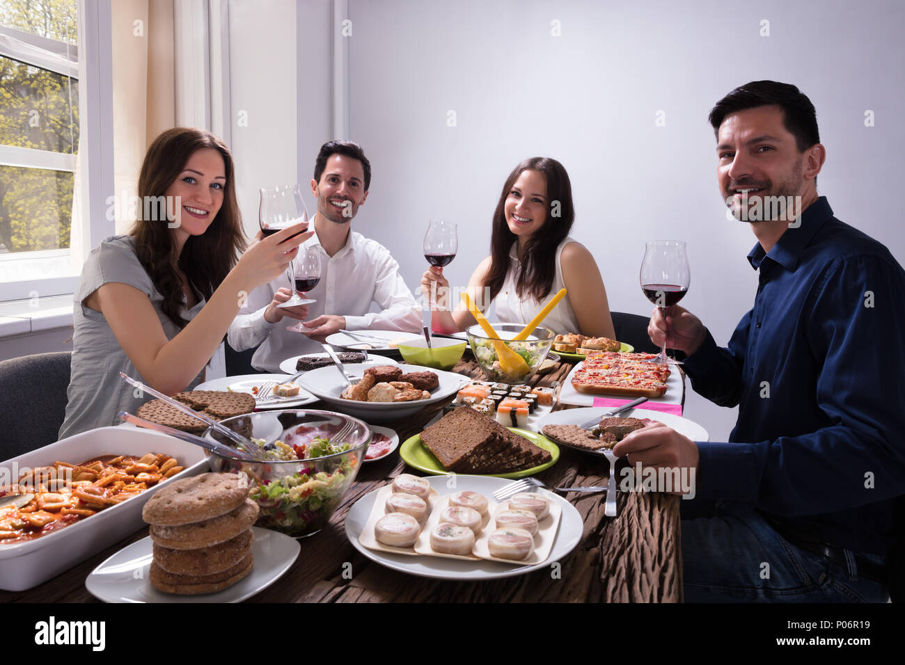 Lächelnden jungen Freunde Essen mit einem Glas Wein im Restaurant Stockfoto