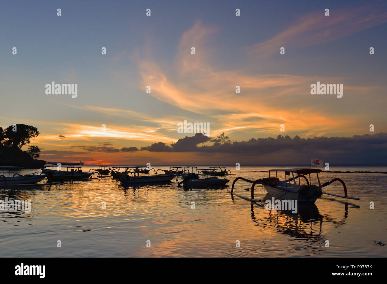 Sonnenuntergang am Strand von Mushroom mit Booten auf dem Meer, Lembongan, Bali, Indonesien Stockfoto