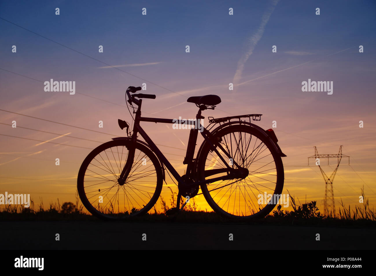 Retro Fahrrad Silhouette am Sonnenuntergang mit Energie Pol im Hintergrund Stockfoto