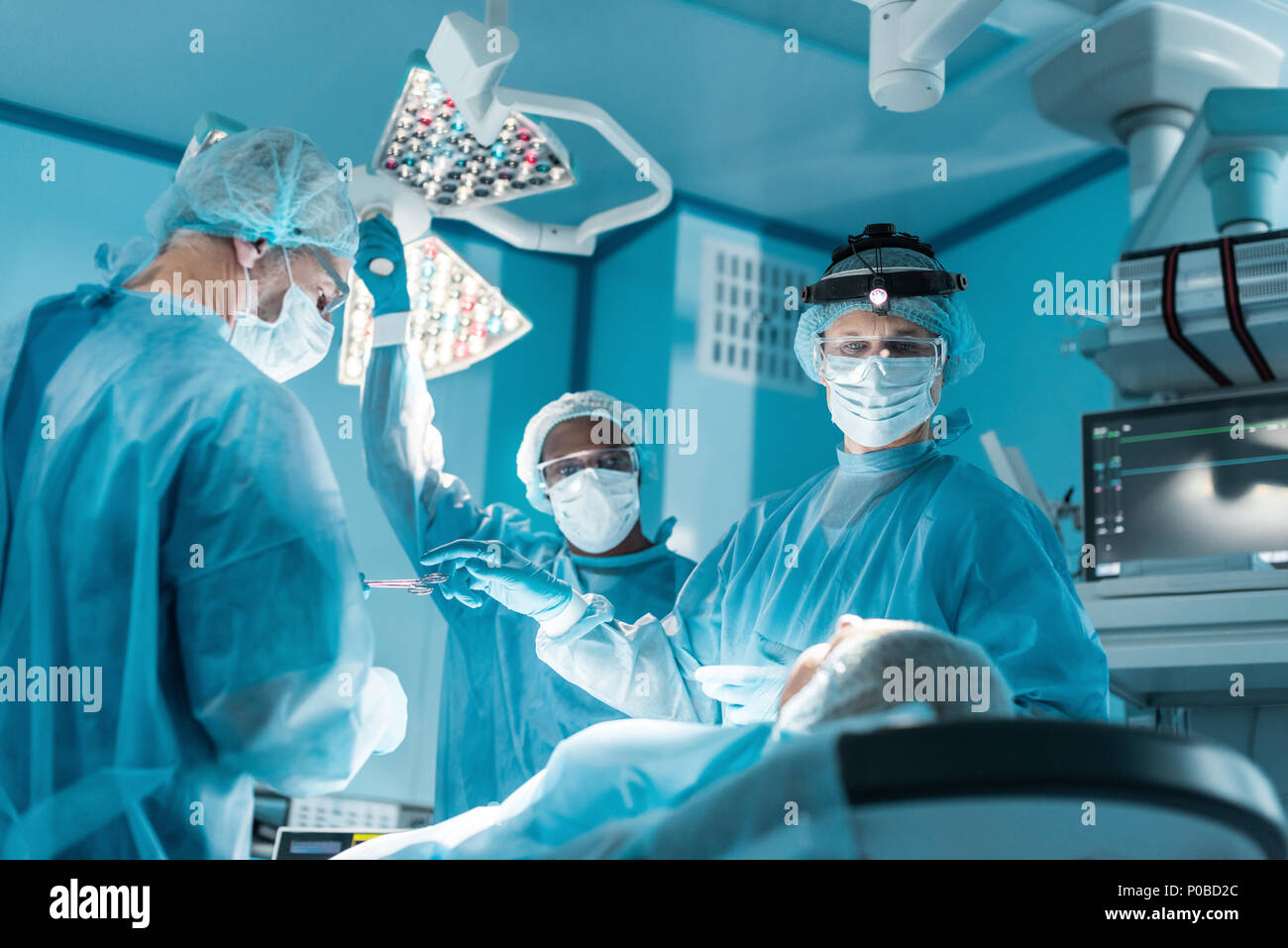 Multikulturelle Chirurgen und Patienten während der Operation im Operationssaal Stockfoto