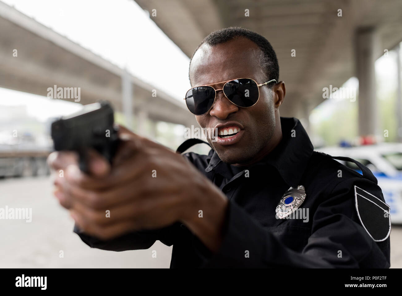 Wütend afrikanische amerikanische Polizisten schreien und die darauf abzielt, durch die Pistole Stockfoto