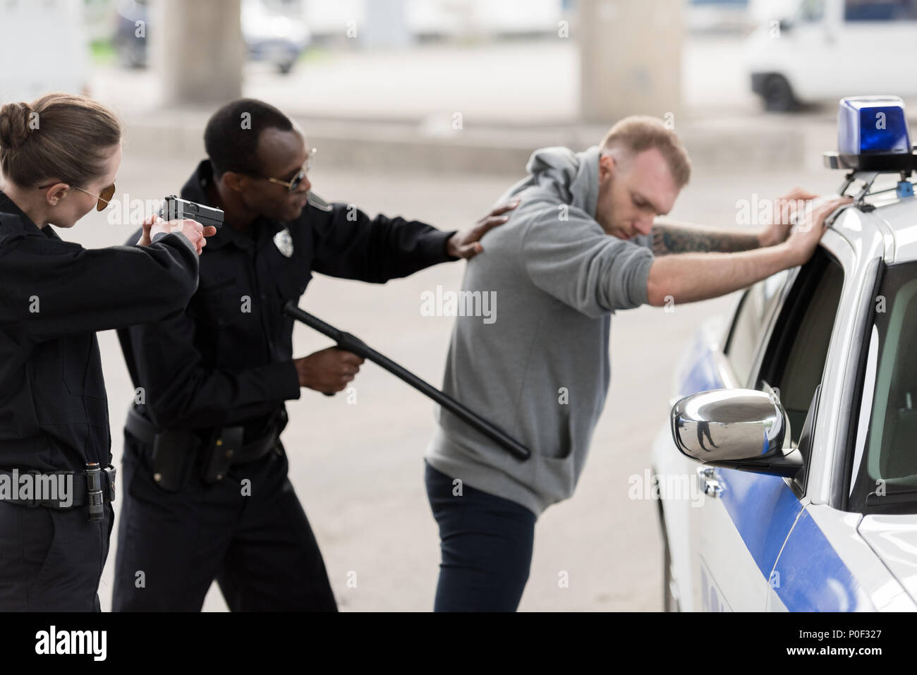 Afrikanische amerikanische Polizisten verhaften junger Mann und Polizistin durch Pistole darauf abzielen, Stockfoto