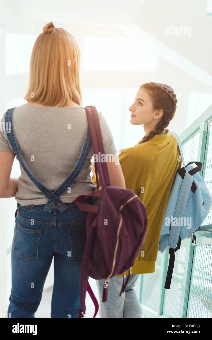 Ansicht der Rückseite des Schülerinnen mit Rucksäcken zu Fuß über Treppen an der Schule Korridor Stockfoto