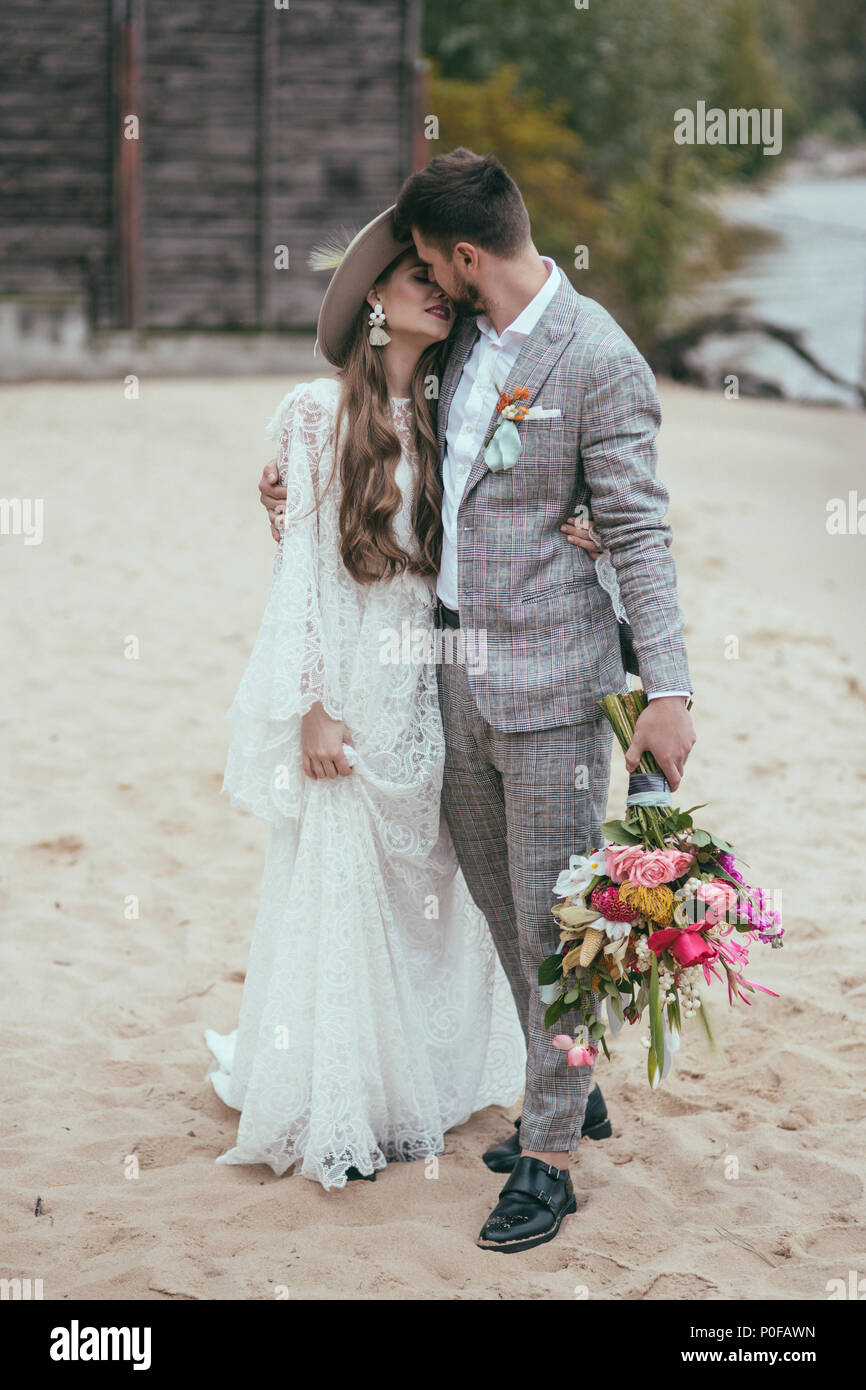 Schöne Braut und Bräutigam in Boho style Küssen auf Strand Stockfoto