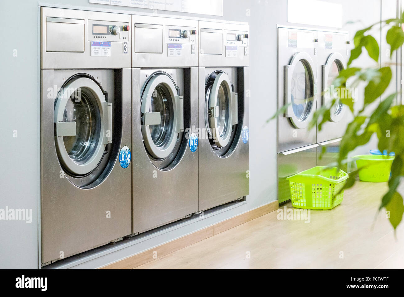 Öffentliche Wäscherei mit modernen, silber Waschmaschinen in einer Reihe Stockfoto