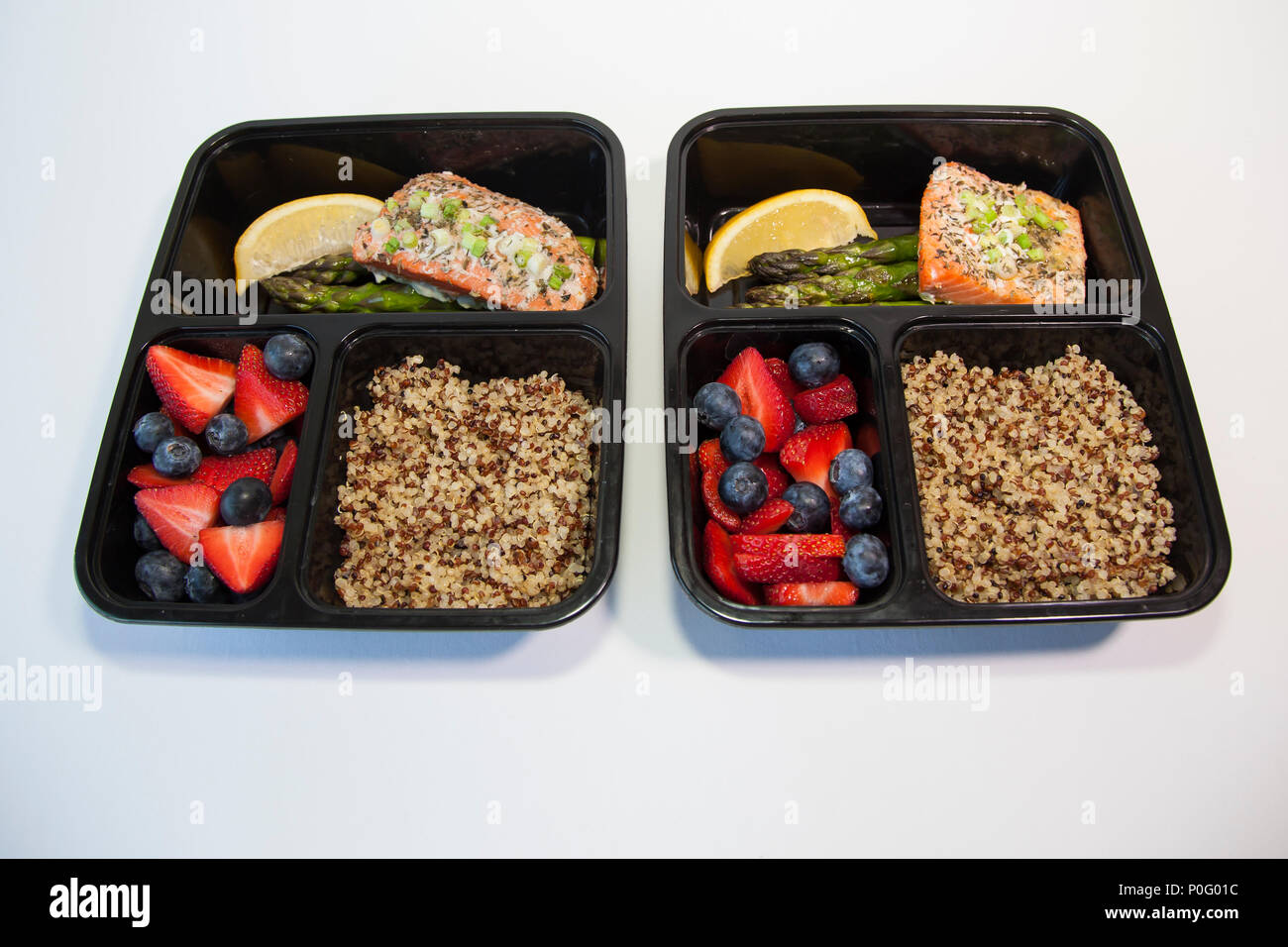 Geplante Mahlzeiten in den Behältern - Lachs mit Spargel, Quinoa und frisches Obst. Stockfoto