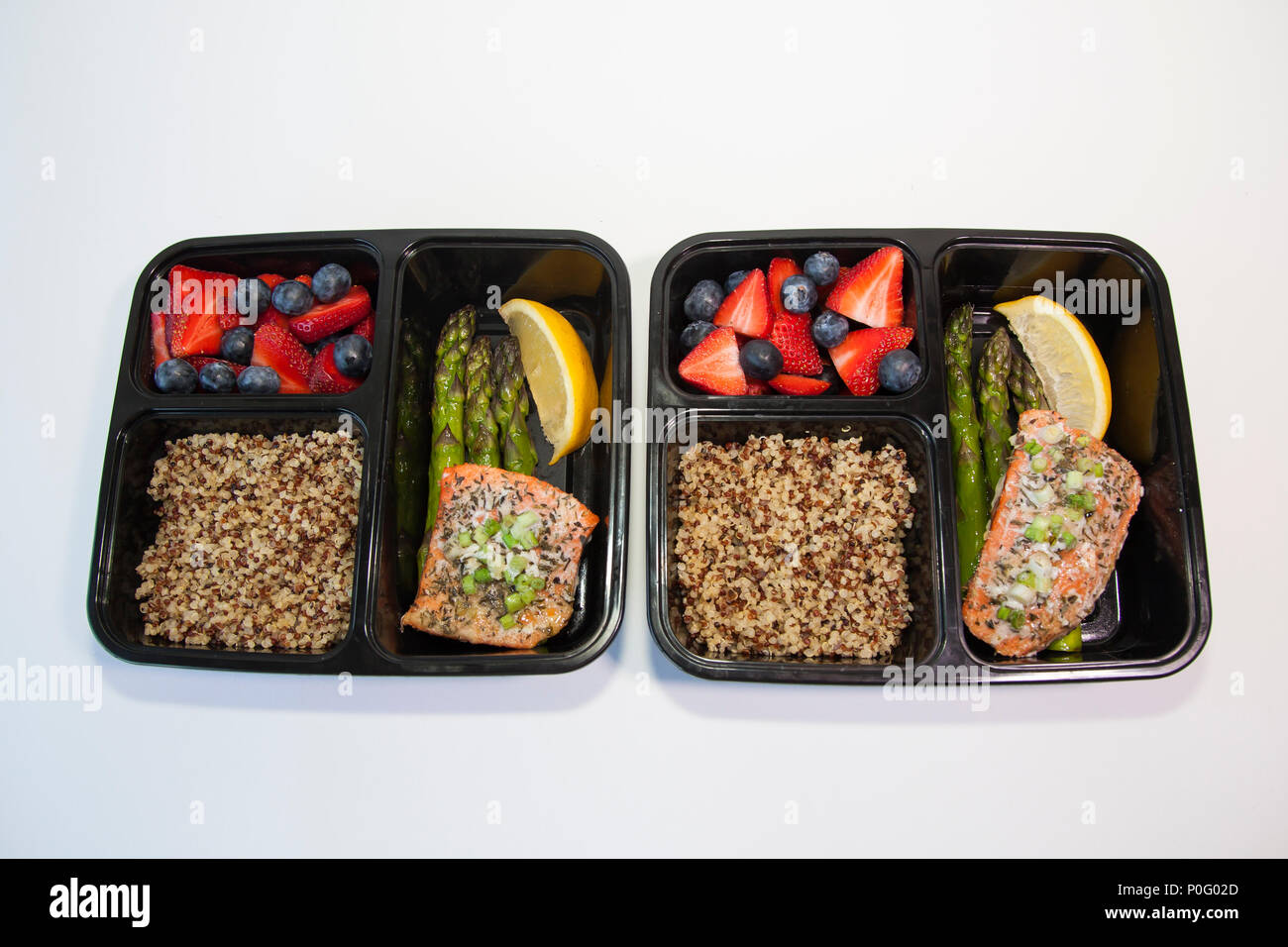 Geplante Mahlzeiten in den Behältern - Lachs mit Spargel, Quinoa und frisches Obst. Stockfoto