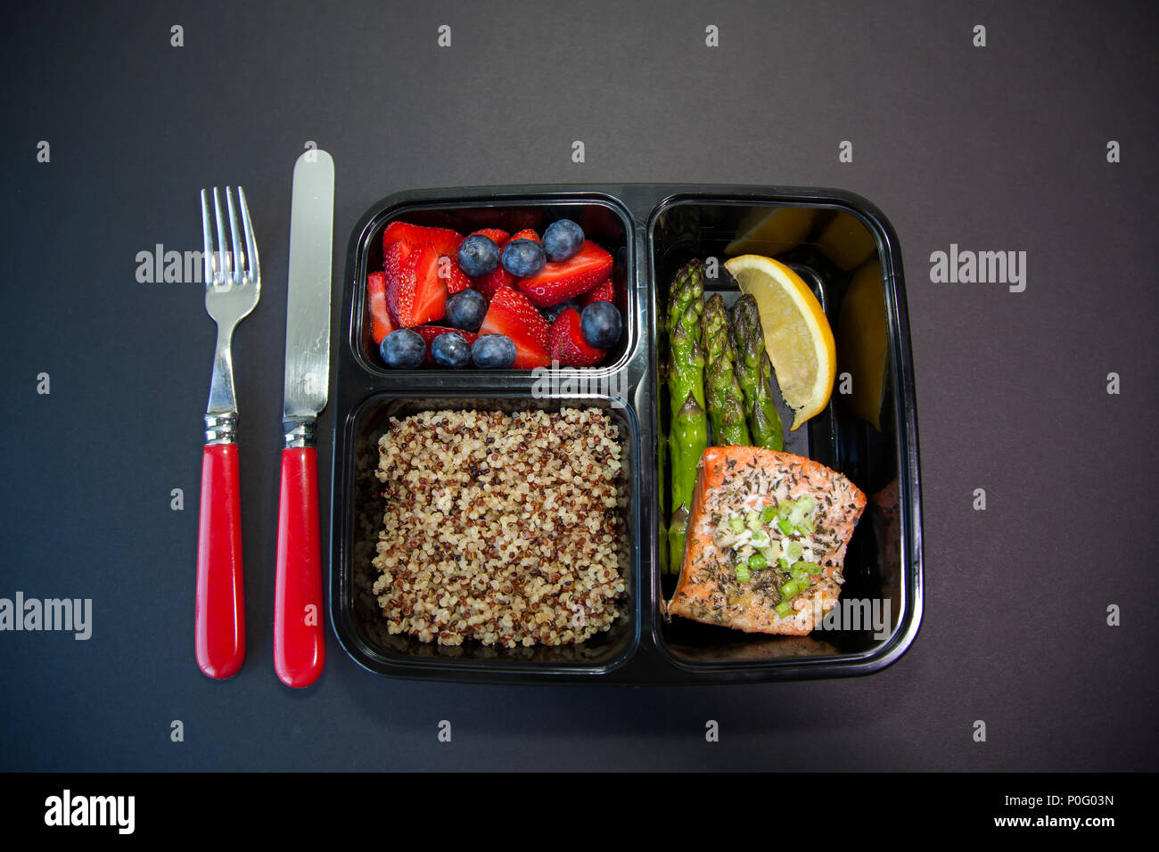 Geplante Mahlzeiten in den Behältern - Lachs mit Spargel, Quinoa und frisches Obst. Stockfoto