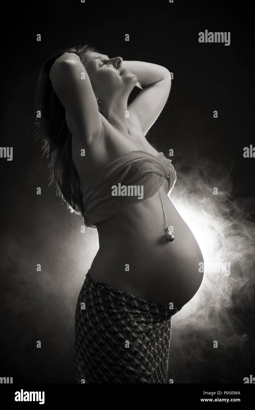 Studio Portrait von schwangeren Frau, Gong Bell ruht auf den Bauch, den Kopf wieder berühren, Haar, Schwarz und Weiß Stockfoto