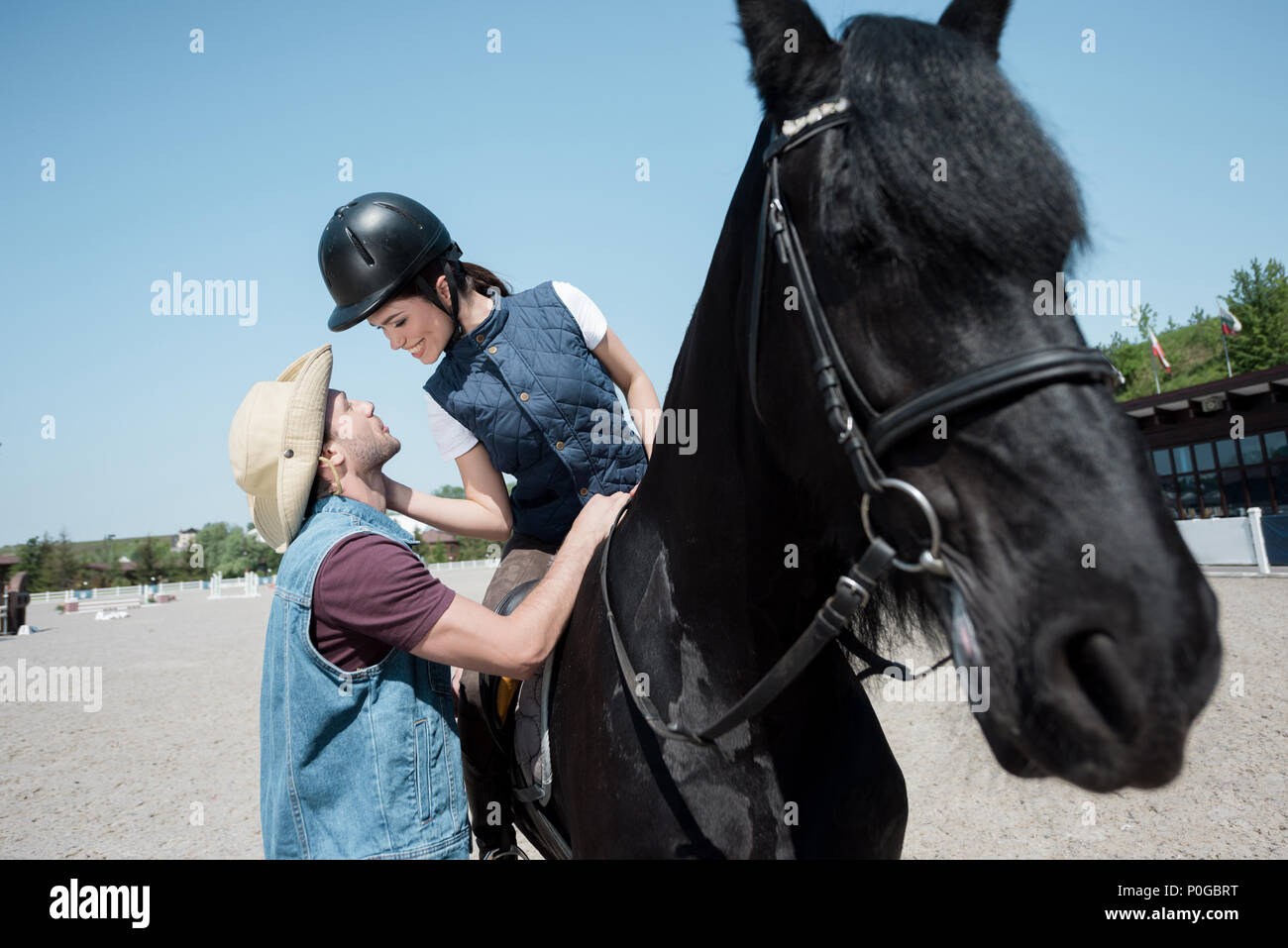 Hübscher junger Mann in Cowboy Hut auf lächelnde Frau in Helm sitzen auf  dem Pferd suchen Stockfotografie - Alamy