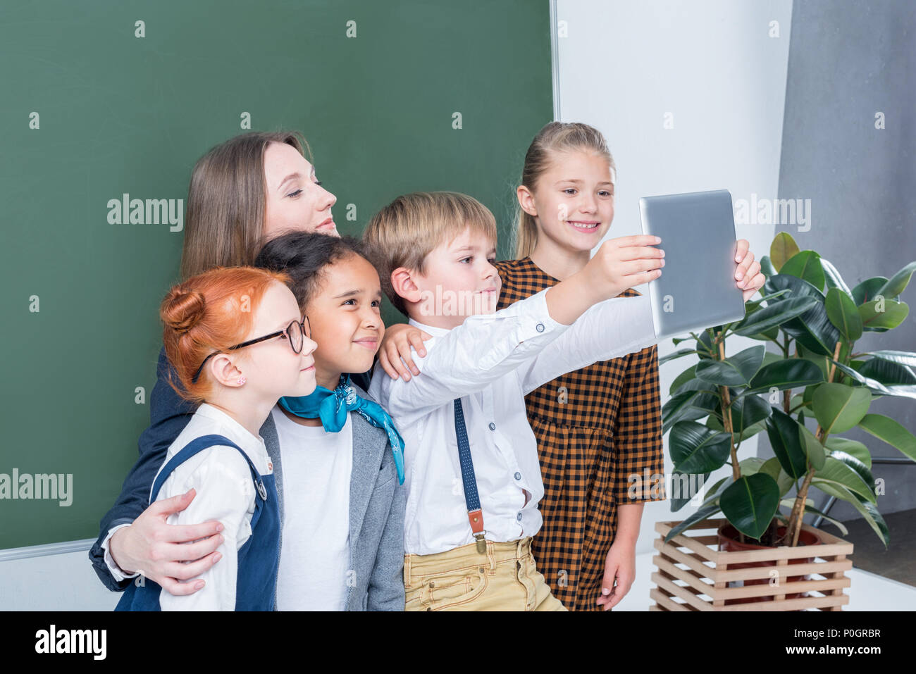 Junge Lehrerin mit niedlichen kleinen Studenten selfie mit digitalen Tablet in der Klasse Stockfoto