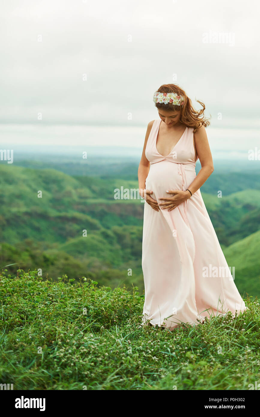 Neues Leben Thema. Junge schwangere Hispanic Frau stand auf Gras Stockfoto