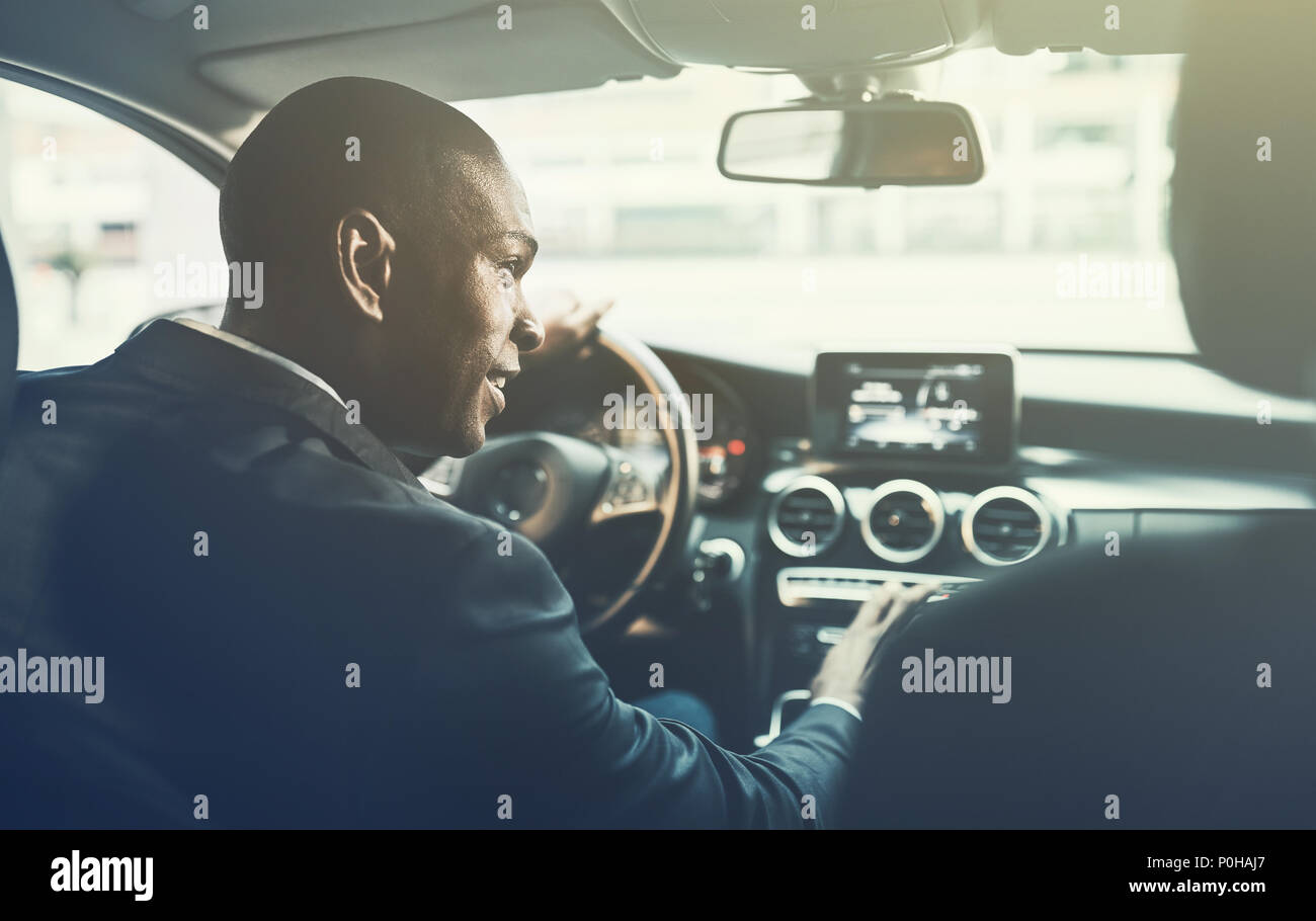 Rückspiegel eines jungen afrikanischen Geschäftsmann ändern Radiosender, während Sie durch die Straßen der Stadt in seinem Auto fahren Stockfoto