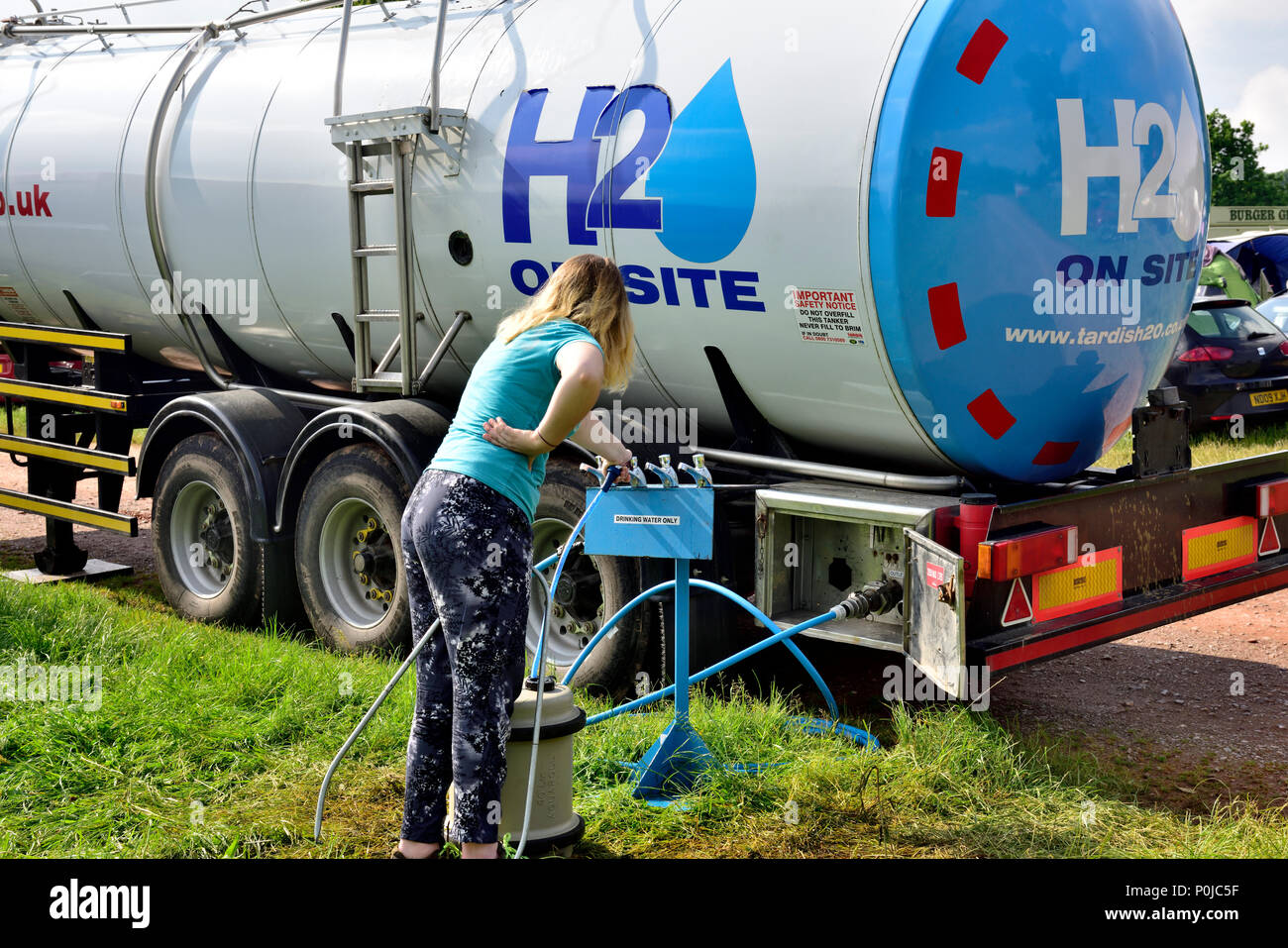 Lady Sammeln von Trinkwasser aus Tankwagen für Camping am Festival Stockfoto
