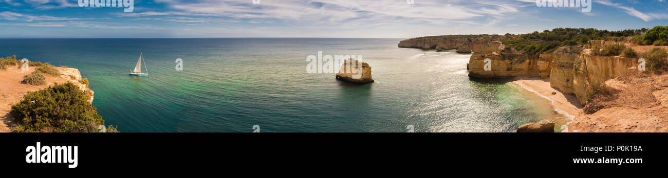 Panorama der Algarve Küste in Portugal mit einem Segelboot auf dem Weg in die Marinha Strand vom Atlantik. Stockfoto