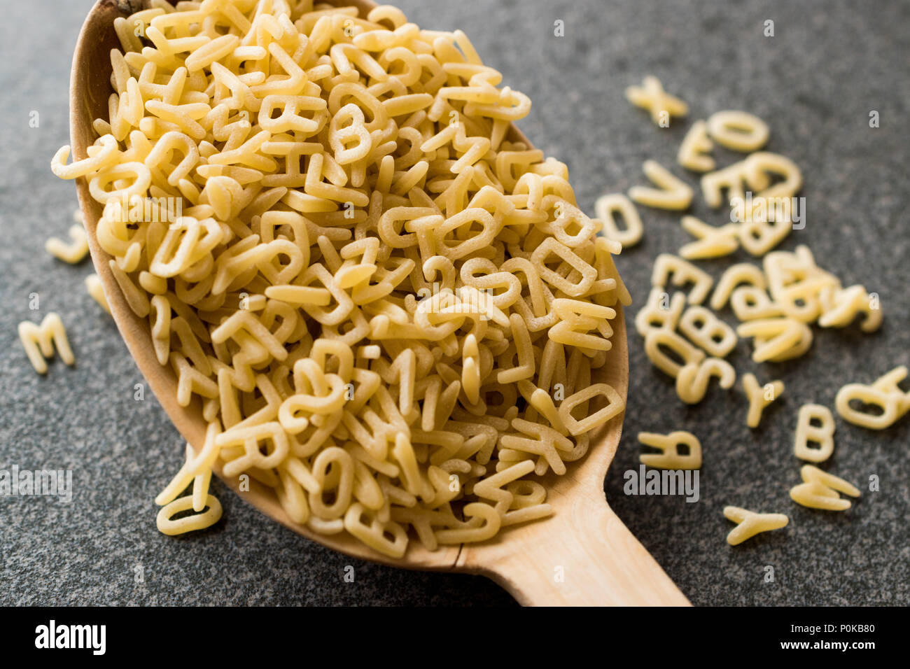 Roh ungekocht Alphabet Nudeln in Löffel aus Holz. Ökologische Lebensmittel. Stockfoto