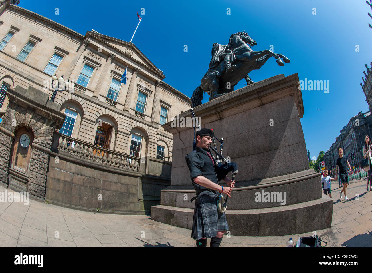 Eine Piper von der Statue des Herzogs von Wellington und der Turm des Balmoral Hotel, Edinburgh, Schottland, Großbritannien Stockfoto