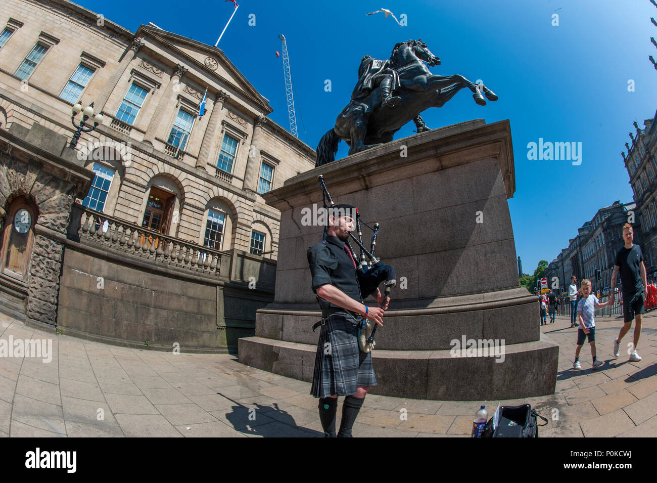 Eine Piper von der Statue des Herzogs von Wellington und der Turm des Balmoral Hotel, Edinburgh, Schottland, Großbritannien Stockfoto