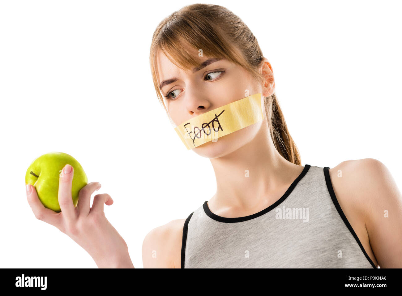 Junge Frau mit Klebeband mit durchgestrichen durch Wort Essen, Mund auf Apfel in der Hand isoliert auf weißem suchen Stockfoto