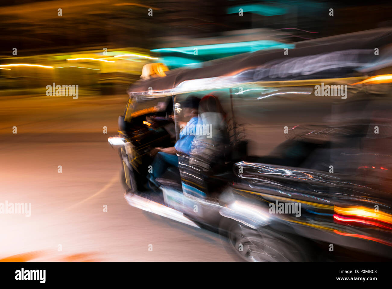 Abstrakte panning Technik schaffen Bewegung&Unschärfe eines Tuktuk taxi Drehen in der Nacht in den Straßen von Chiang Mai im Norden von Thailand links Stockfoto
