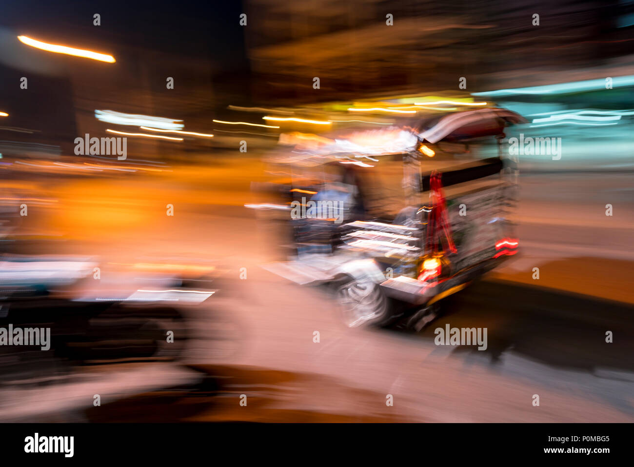Abstrakte panning Technik schaffen Bewegung&Unschärfe eines Tuktuk racing Vergangenheit in der Nacht in den Straßen von Chiang Mai im Norden von Thailand Stockfoto
