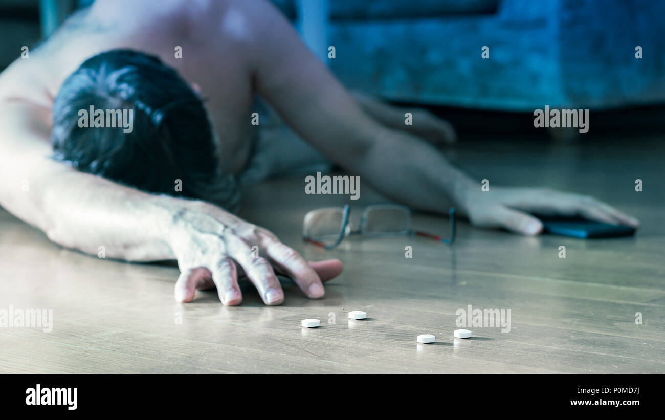 Selbstmord attemp Konzept: reifer Mann auf dem Boden zu Hause liegen für eine Überdosierung nach Pillen. Stockfoto