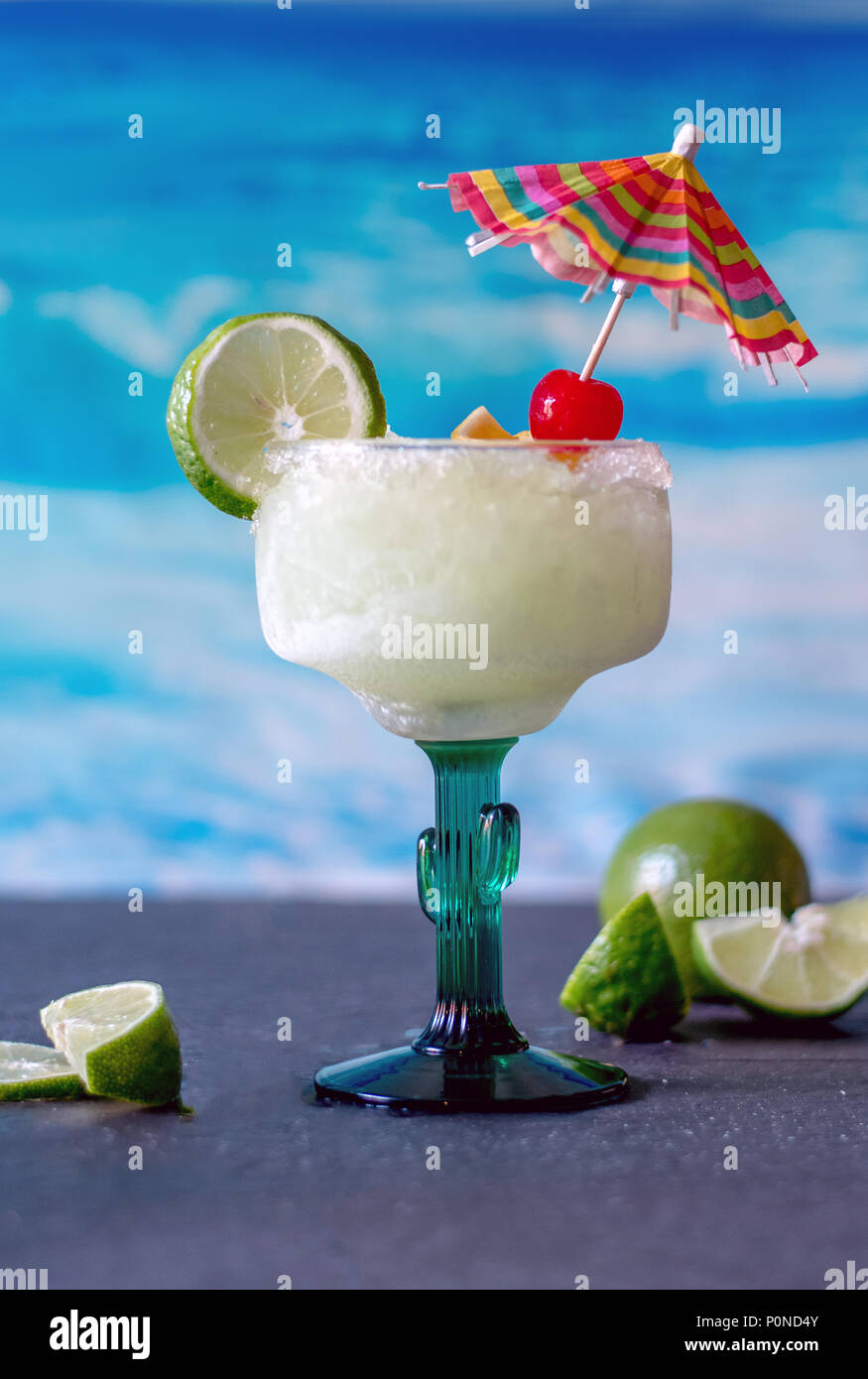 Lecker frozen margarita Getränke mit Kalk und Kirsche garnieren und einen farbenfrohen Drink Regenschirm Stockfoto